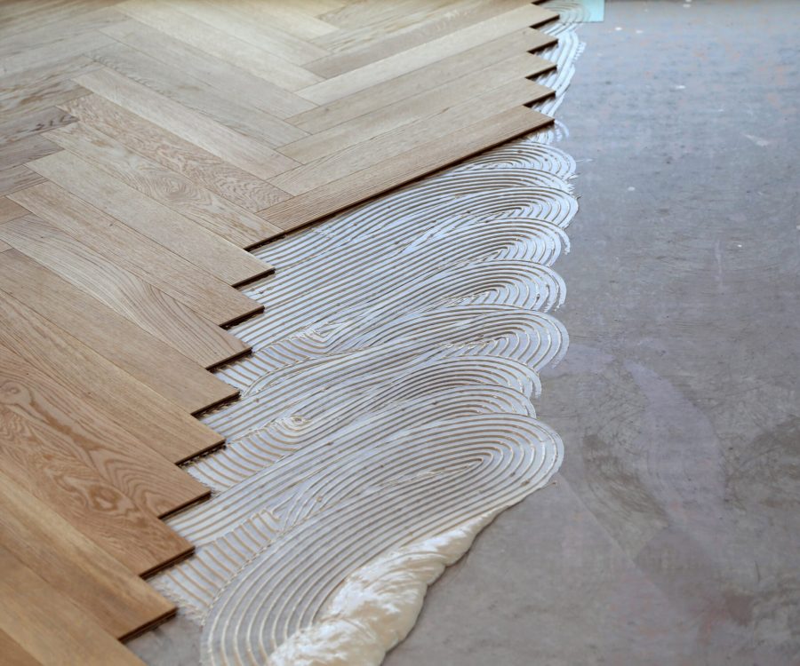 A worker laying parquet flooring and installing wooden laminate